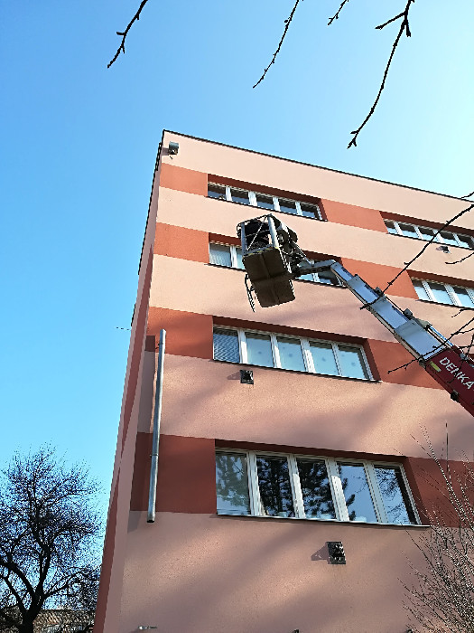 Práce z plošiny na fasádě bytového domu